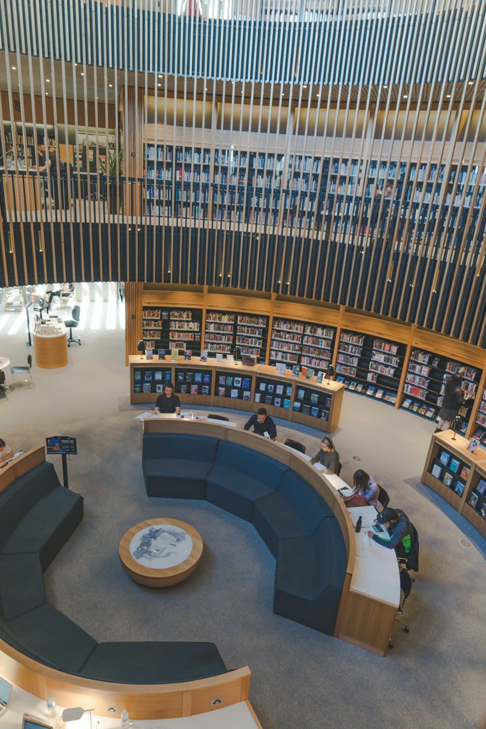 Persone che studiano e sistemano libri in una biblioteca moderna.